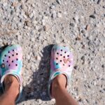 Colorful modern clogs decorated with butterfly charms photographed on gravel