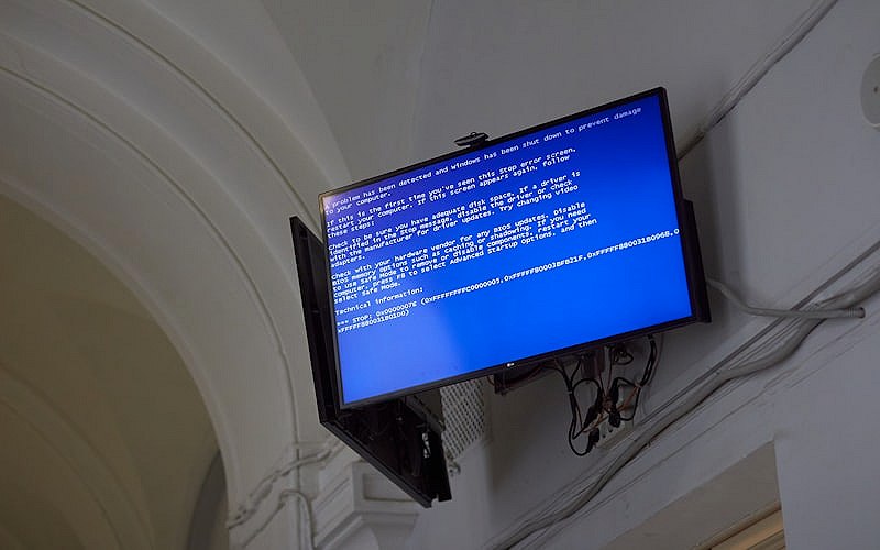 Large screen displaying a blue screen of death error in a dimly lit room representing system failure